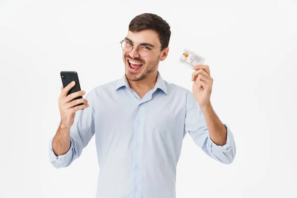 Photo Delighted Man Eyeglasses Holding Cellphone Credit Card Isolated White — Stock Photo, Image