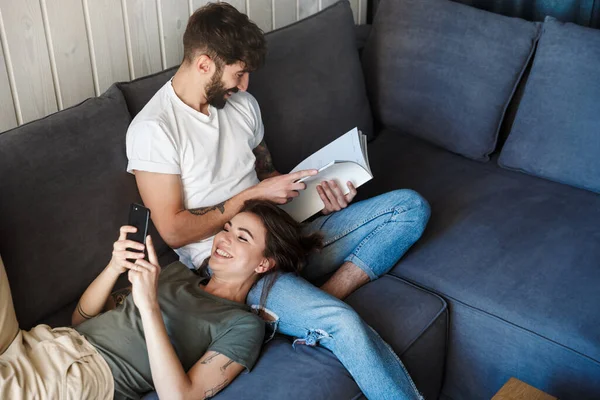 Usmívající Mladý Krásný Pár Relaxující Gauči Obývacím Pokoji Muž Čtení — Stock fotografie