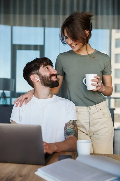 Hermosa Pareja Joven Sonriente Usando Computadora Portátil Mientras Pasa Tiempo —  Fotos de Stock