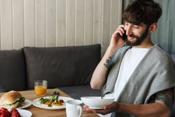 Atractivo Sonriente Joven Barbudo Hombre Usando Teléfono Móvil Mientras Tiene — Foto de Stock