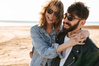 Genç ve güzel bir çift güneşli sahilde harika vakit geçiriyorlar, sarılıyorlar.