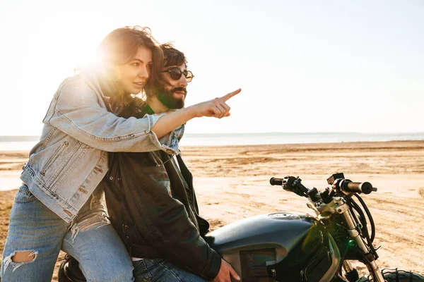 Piękna Para Yong Nosząca Kurtki Siedząca Motocyklu Słonecznej Plaży Wskazująca — Zdjęcie stockowe