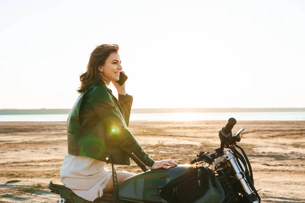Красивая Молодая Девушка Кожаной Куртке Сидит Мотоцикле Солнечном Пляже Разговаривает — стоковое фото