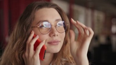 Konferans salonunda otururken genç ve güzel bir bayanın yakın plan görüntüsü telefonda konuşuyor.