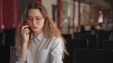 Genç ve güzel bir kadın konferans salonunda otururken telefonla konuşuyor.