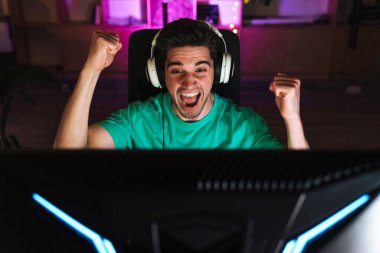 Kulaklıklı heyecanlı bir gencin evde bilgisayar oyunu oynarken yaptığı jest.