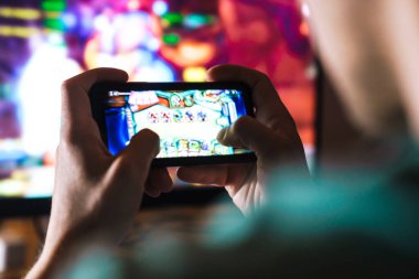 Evde cep telefonu ve bilgisayarda video oyunu oynayan odaklanmış adamın görüntüsü
