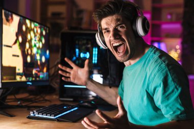 Evde bilgisayar oyunu oynarken kulaklıklı öfkeli bir gencin çığlığı.