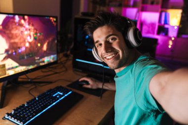 Kafkasyalı neşeli bir adamın evde bilgisayar oyunu oynarken selfie çekerken görüntüsü