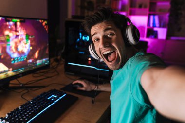 Kafkasyalı heyecanlı bir adamın evde bilgisayar oyunu oynarken selfie çekmesi