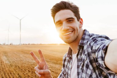 Mutlu adam rüzgar türbinleriyle sanayi bölgesine selfie çekiyor.