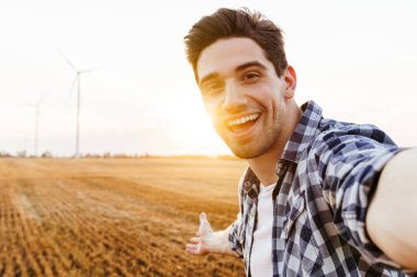 Mutlu adam rüzgar türbinleriyle sanayi bölgesine selfie çekiyor.