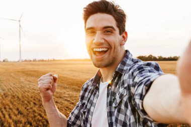 Mutlu adam rüzgar türbinleriyle sanayi bölgesine selfie çekiyor.