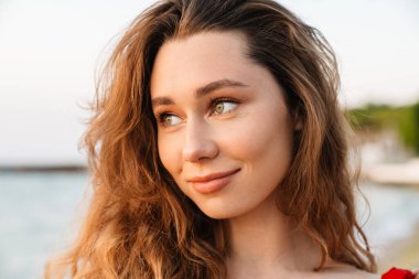 Kumsalda bikini giyen güzel, gülümseyen genç bir kadın. Yaklaş.