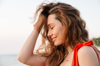 Kumsalda bikini giyen güzel, gülümseyen genç bir kadın. Yaklaş.