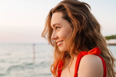 Kumsalda bikini giyen güzel, gülümseyen genç bir kadın. Yaklaş.