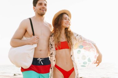 Romantik genç çift güneşli sahilde birlikte yürüyor.