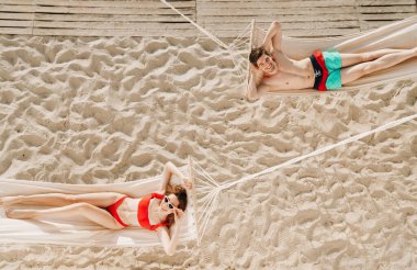 Genç ve romantik bir çiftin plajdaki hamaklarda dinlenmesinin en güzel görüntüsü.