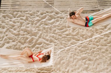 Genç ve romantik bir çiftin plajdaki hamaklarda dinlenmesinin en güzel görüntüsü.