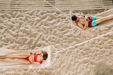 Genç ve romantik bir çiftin plajdaki hamaklarda dinlenmesinin en güzel görüntüsü.