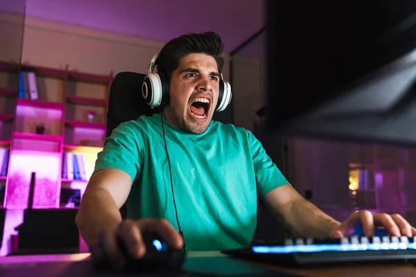 Imagen Del Joven Sorprendido Auriculares Gritando Mientras Juega Videojuego Ordenador —  Fotos de Stock