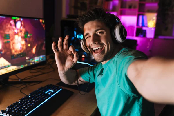 Evdeki bilgisayarda bilgisayar oyunu oynarken işaret diliyle resim çeken neşeli bir adam resmi