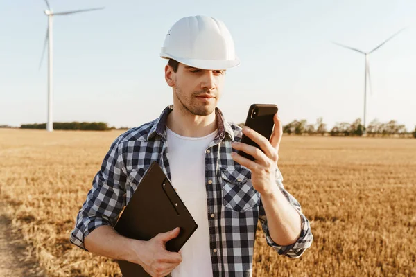 Elektrikli Yel Değirmeni Çiftliğinde Dururken Cep Telefonu Kullanan Gülümseyen Bir — Stok fotoğraf