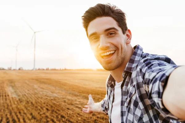 Mutlu adam rüzgar türbinleriyle sanayi bölgesine selfie çekiyor.