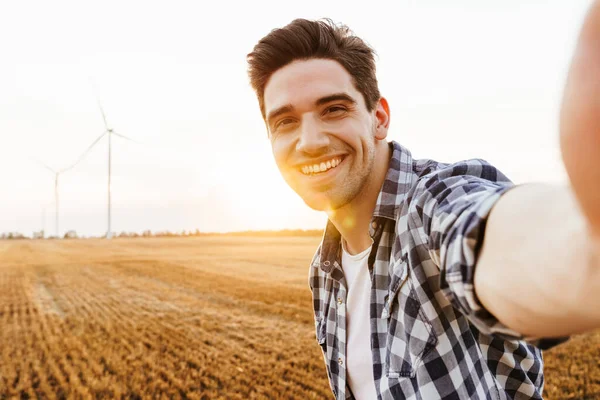 Mutlu adam rüzgar türbinleriyle sanayi bölgesine selfie çekiyor.