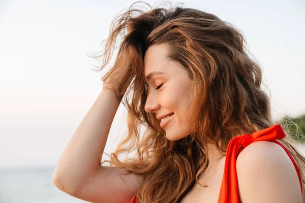 Kumsalda bikini giyen güzel, gülümseyen genç bir kadın. Yaklaş.