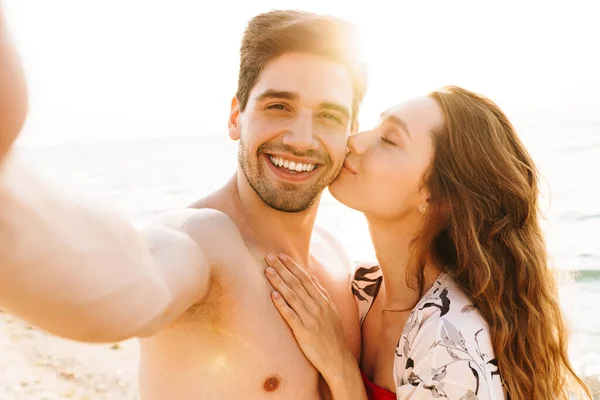 一对快乐的夫妇在度假期间在海滩拍照 — 图库照片