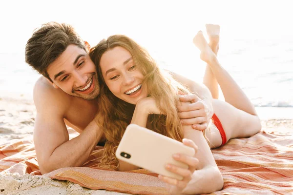 Ευτυχισμένο Νεαρό Ζευγάρι Βγάζει Μια Selfie Στην Παραλία Ενώ Ξαπλώνει — Φωτογραφία Αρχείου