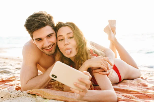 Ευτυχισμένο Νεαρό Ζευγάρι Βγάζει Μια Selfie Στην Παραλία Ενώ Ξαπλώνει — Φωτογραφία Αρχείου