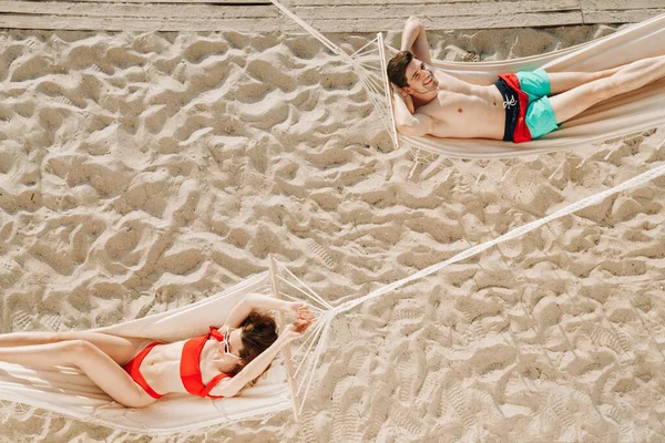Genç ve romantik bir çiftin plajdaki hamaklarda dinlenmesinin en güzel görüntüsü.