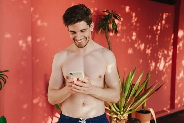 Lachende Knappe Man Ontspannen Het Strand Met Zijn Mobiele Telefoon — Stockfoto