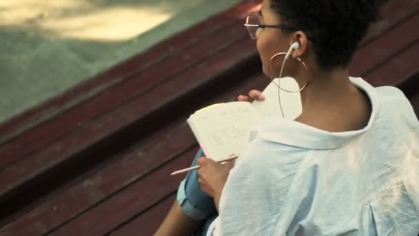 Baksida Lugn Ung Afrikansk Amerikansk Kvinna Gör Anteckningar Sitter Bänken — Stockvideo