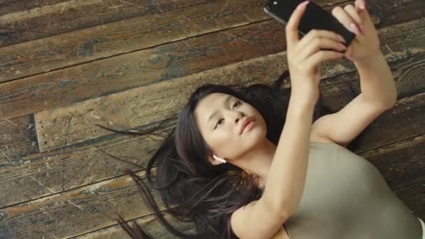 一番上から見た美しいアジア系の若い女性の姿は 自宅の床に置かれた自撮り写真 — ストック動画