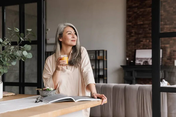 Image Mature Woman Sitting Kitchen Indoors Home While Reading Book — Stock Photo, Image