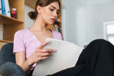 Ofis içinde kitap okuyan konsantre güzel kadın tasarımcı resmi