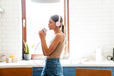 Mutfakta dans eden, kulaklıkla müzik dinleyen, cep telefonu tutan genç, inanılmaz duygusal bir kadın.
