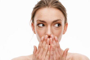 Beyaz arka planda elleri izole bir şekilde ağzını kapatan beyaz, beyaz, genç ve güzel bir kadının görüntüsü.