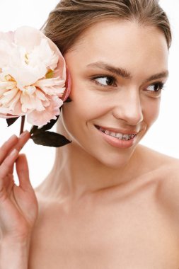 Beyaz arka planda saklanmış şakayık çiçeğini tutan güzel beyaz, beyaz, mutlu, üstsüz bir kadın resmi.