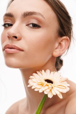 Beyaz arka planda izole edilmiş Alman çiçeğini tutan güzel, beyaz, beyaz, mutlu, üstsüz bir kadının görüntüsü.