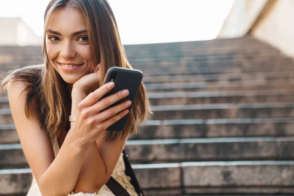 Foto Uma Jovem Mulher Feliz Sentada Degraus Livre Enquanto Usa — Fotografia de Stock