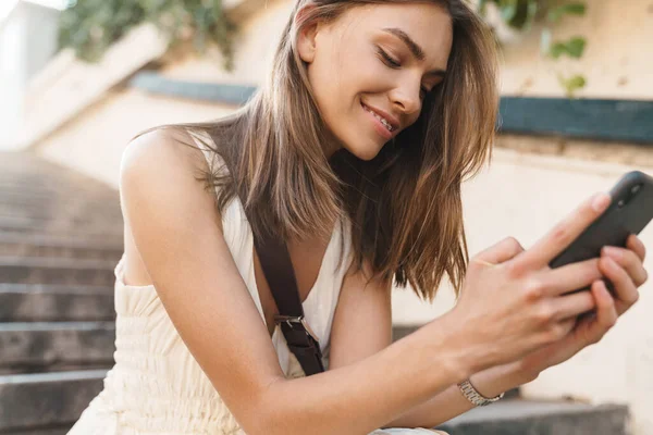 Foto Uma Jovem Mulher Feliz Sentada Degraus Livre Enquanto Usa — Fotografia de Stock