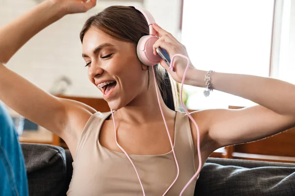 Atractiva Joven Alegre Escuchando Música Con Auriculares Sentada Sofá — Foto de Stock