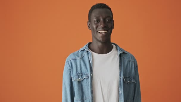 Гарний Емоційний Афроамериканський Молодий Чоловік Сміється Стоїть Ізольовано Помаранчевому Тлі — стокове відео