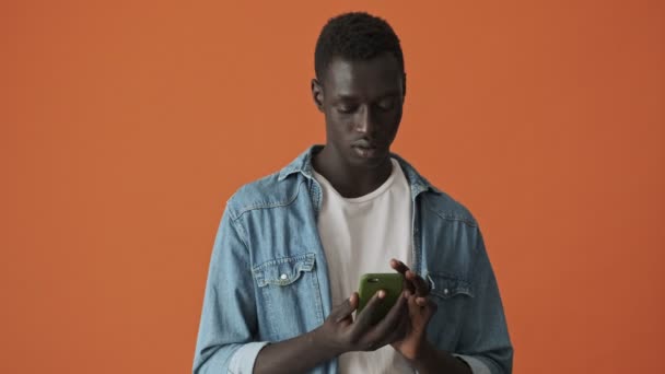 Jovem Afro Americano Surpreso Satisfeito Está Digitando Seu Smartphone Isolado — Vídeo de Stock