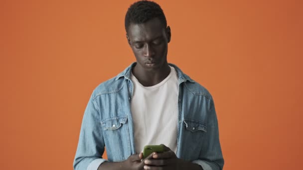 Недовольный Африканский Американский Молодой Человек Печатает Своем Смартфоне Изолированно Стоя — стоковое видео