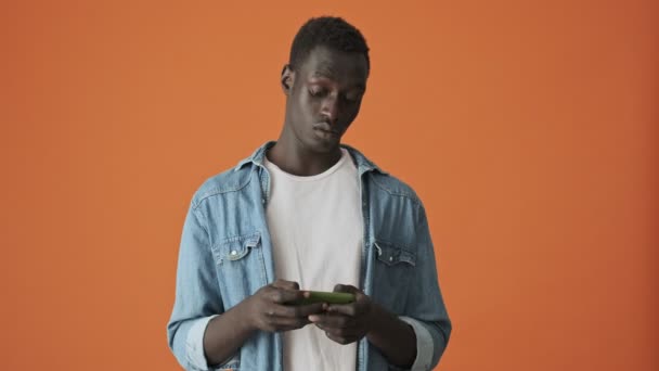 Joven Afroamericano Emocional Positivo Está Jugando Teléfono Inteligente Pie Aislado — Vídeos de Stock